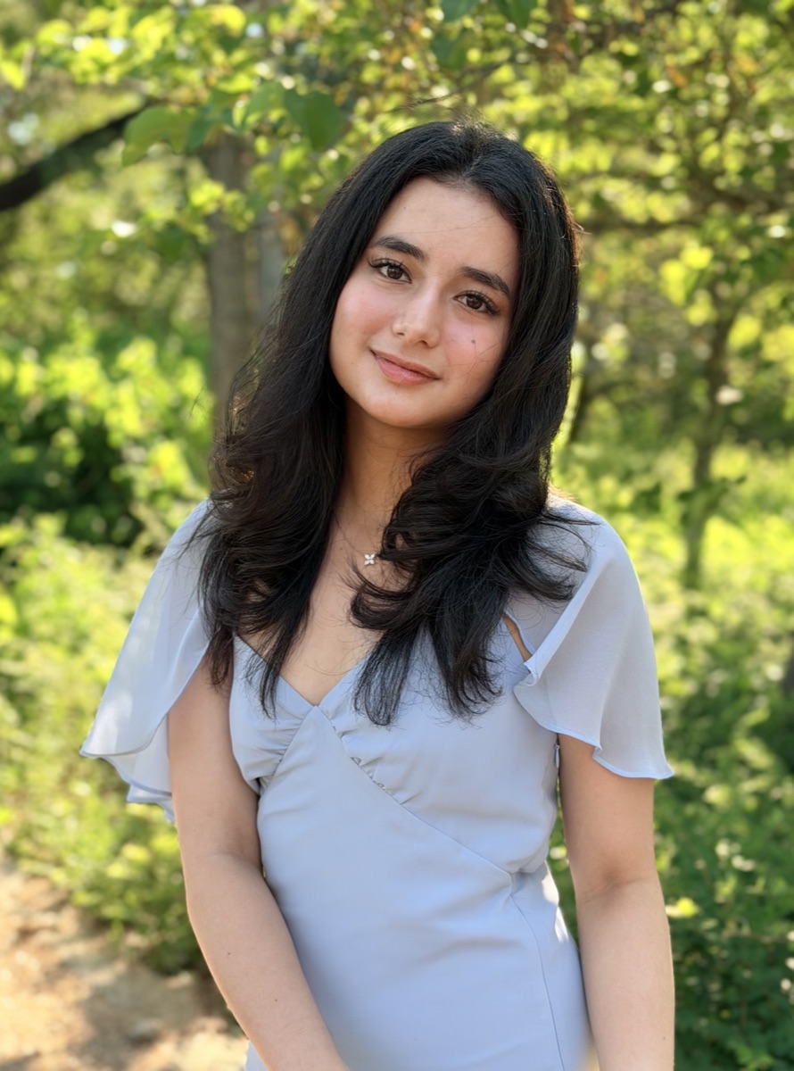 Portrait of Chloe Cheuk outdoors in front of green trees.